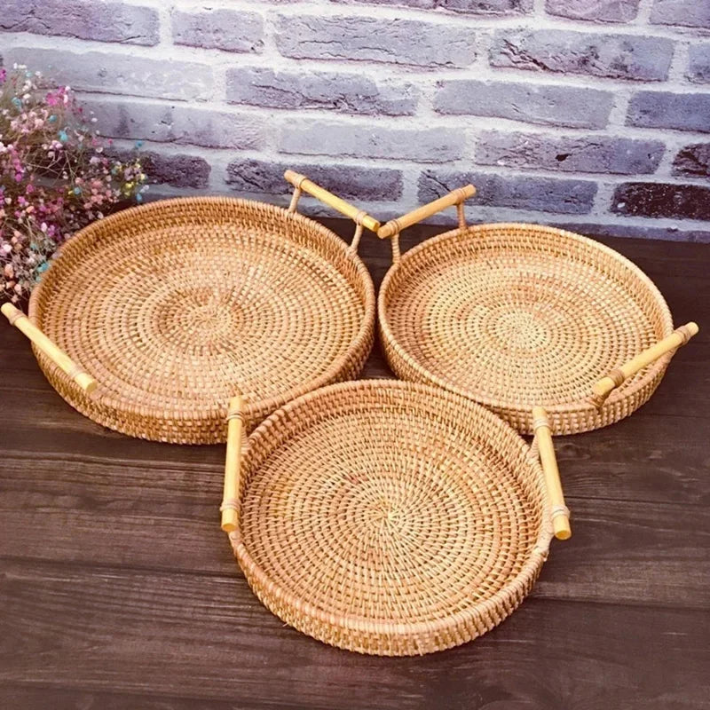 3 cestos de palha de vime rattan com alça sobre mesa, com flores coloridas à esquerda